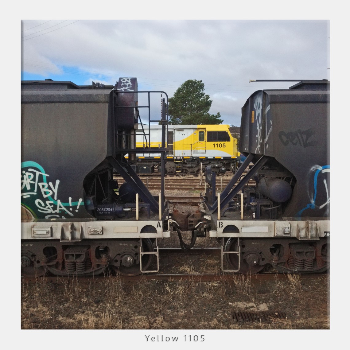 Yellow locomotive flanked by grain freighters taken using DNG on iPhone Pro 10.5